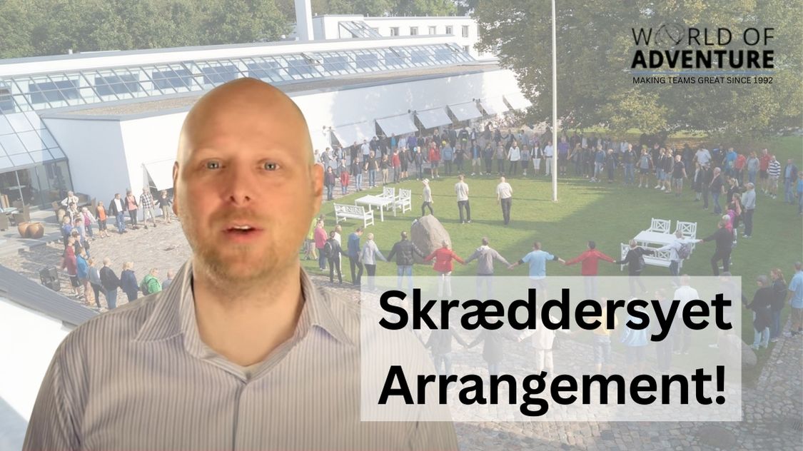Billedet viser et stort firmaarrangement, hvor deltagerne står i en stor cirkel og holder hinanden i hånden foran en moderne bygning. I forgrunden ses en mand, der præsenterer konceptet, mens teksten "Skræddersyet Arrangement!" fremhæver, at eventet er tilpasset den enkelte virksomheds behov. Stemningen er åben og inkluderende – perfekt til teambuilding og fællesskab.